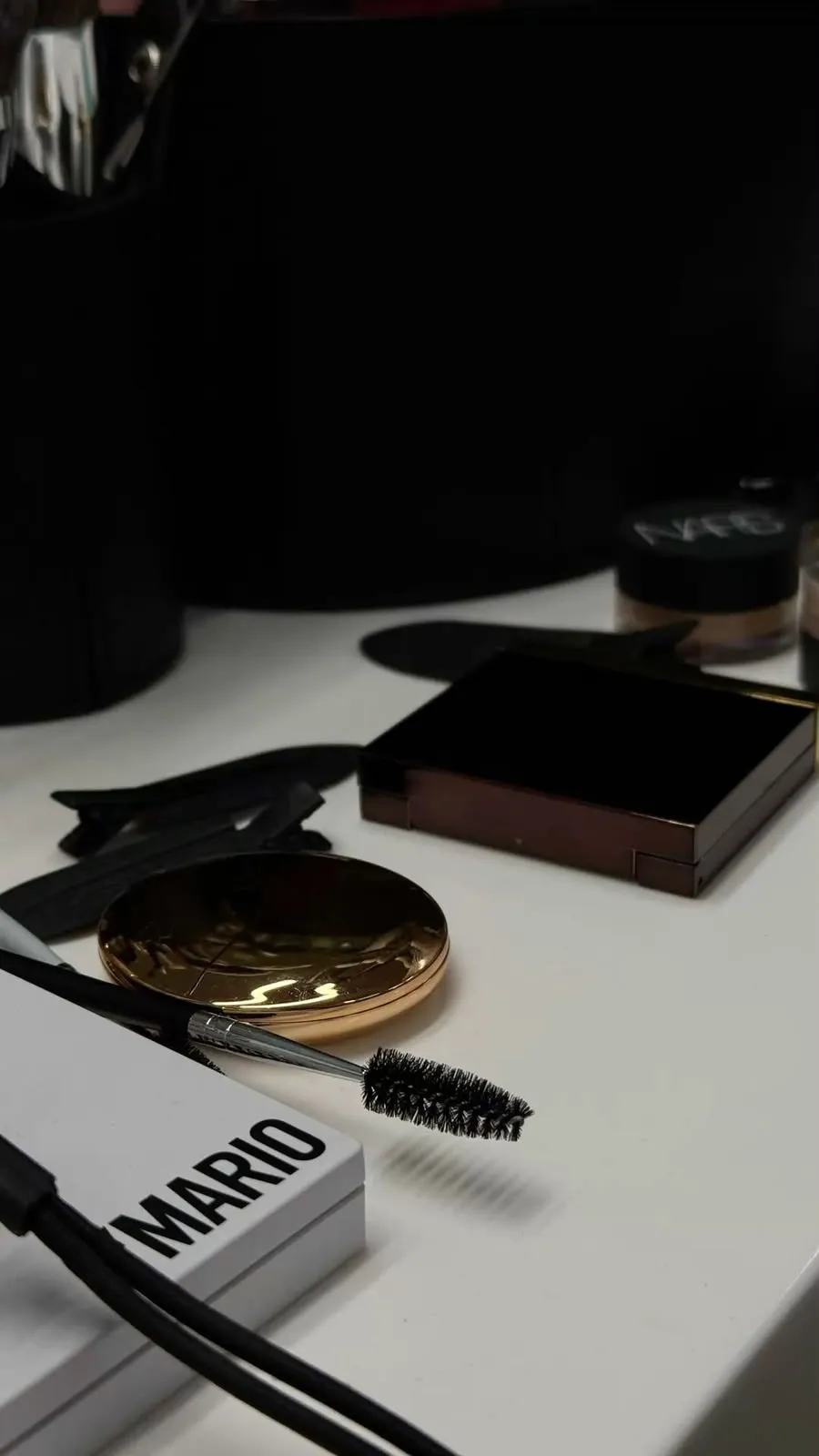 Makeup brushes, mascara and palette on a white vanity