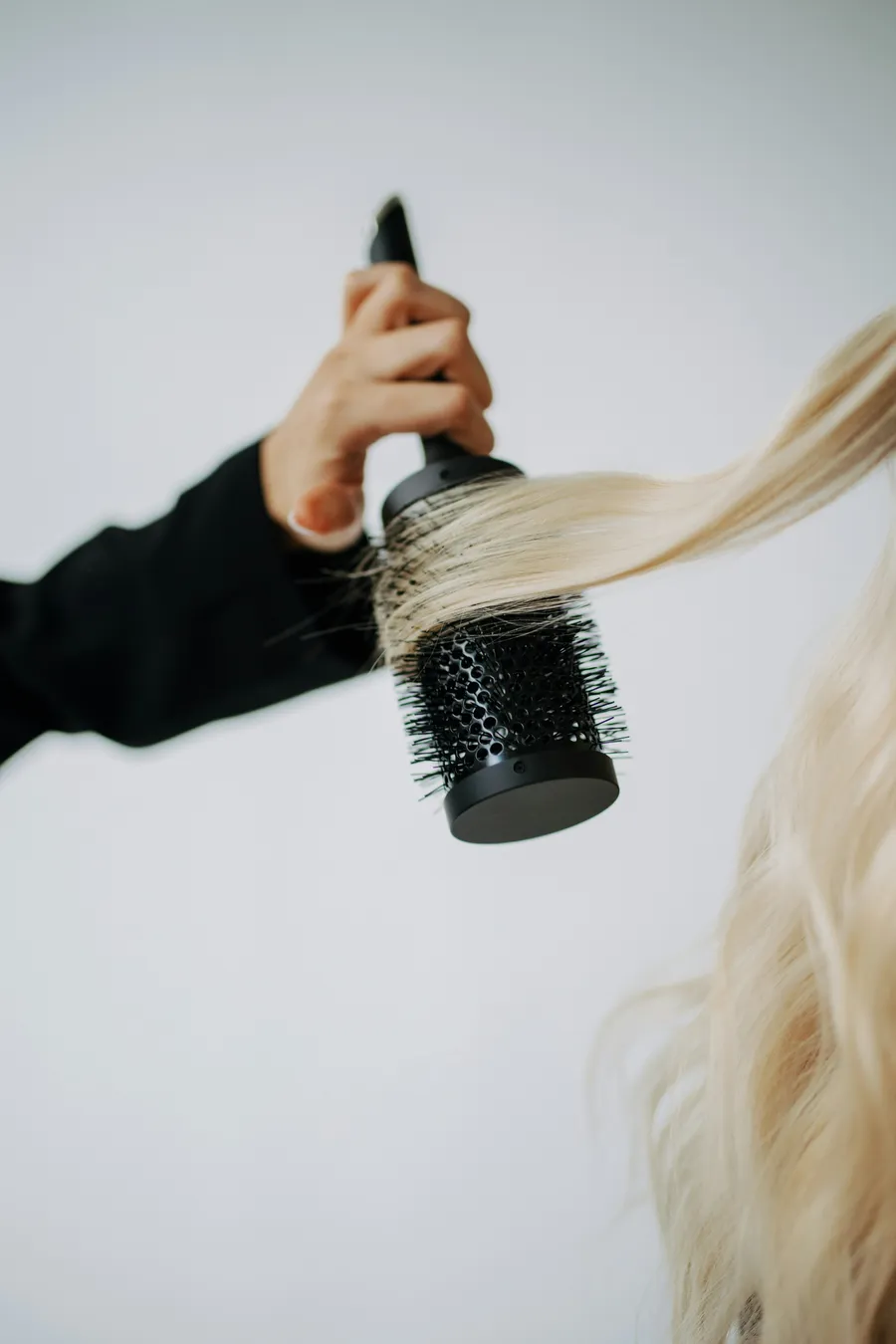 A round brush working through long blonde hair